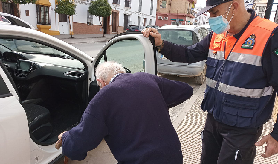 Un voluntario de Protección Civil de Puebla de Cazalla ayuda a un anciano.